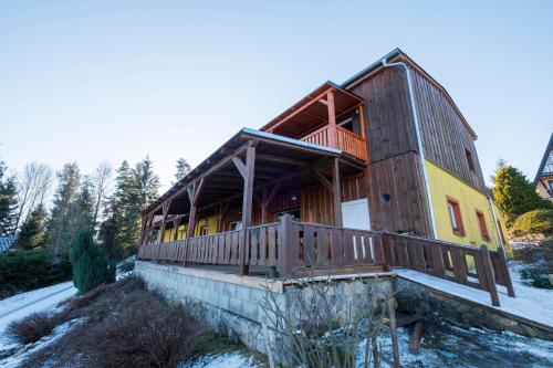 a large wooden house with a deck on a snow covered yard at Panorama Kobylnice in Lipno nad Vltavou
