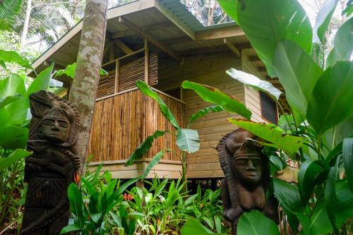 two statues in front of a wooden house at Rainbow Lodge Costa Rica in Savegre