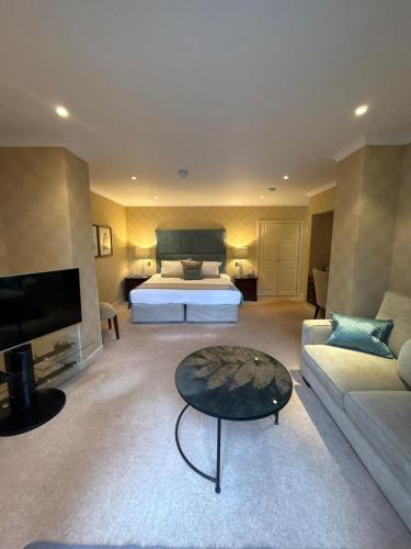 a bedroom with a bed and a couch and a table at The Airds Hotel and Restaurant in Port Appin