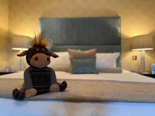 a stuffed cow toy sitting on a bed at The Airds Hotel and Restaurant in Port Appin