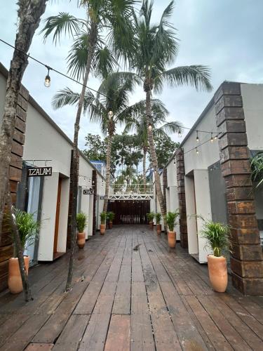 a wooden walkway with palm trees in front of a building at Alquimia Hotel Boutique in Tulum