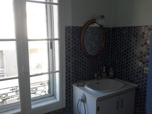 une salle de bain avec un lavabo, un miroir et une fenêtre dans l'établissement Rue sebastien spacious apartment close beach, à Banyuls-sur-Mer