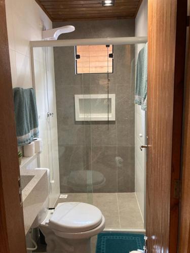 a bathroom with a toilet and a glass shower at Pousada Chalé Flor de Hibisco 1 in Penha