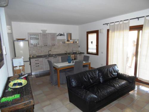 uma sala de estar com um sofá de couro e uma cozinha em Trilocale I Meridiani Le Maree 4T em Cannigione