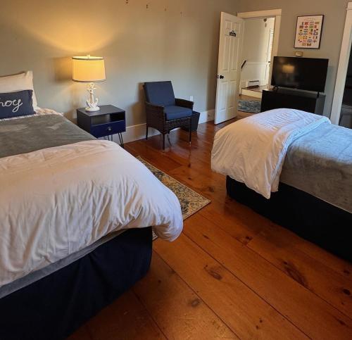 a bedroom with two beds and a chair and a television at White Sails Inn in Kennebunk