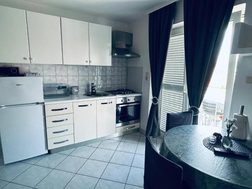 eine Küche mit weißen Schränken und einem Tisch darin in der Unterkunft Cosy apartment in Pag / 26 m² / Sea view in Pag