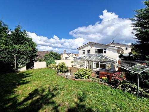 a house with a glass greenhouse in a yard at Spacious Four Bedroom House, 3 min walk to beach in Paignton