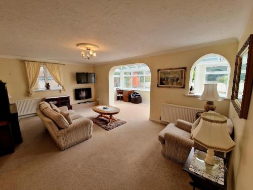 a living room with two chairs and a table at Spacious Four Bedroom House, 3 min walk to beach in Paignton
