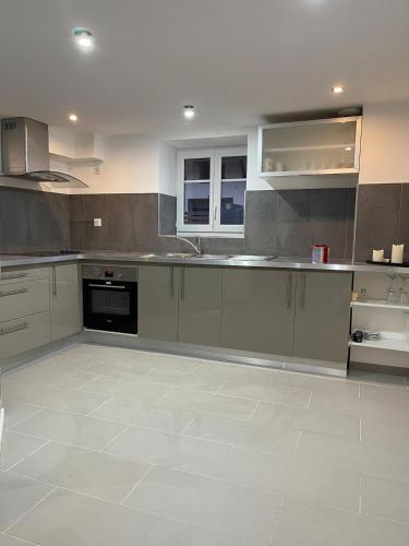 Il comprend une cuisine avec des placards gris et du carrelage blanc. dans l'établissement Charmante maison, à Ottmarsheim