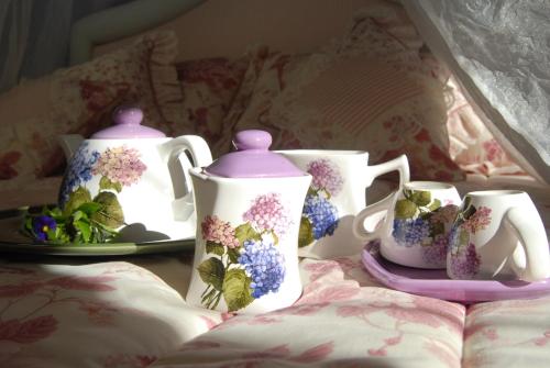 a group of tea pots and cups on a bed at La Dimora le Fumarole Rooms in Ercolano