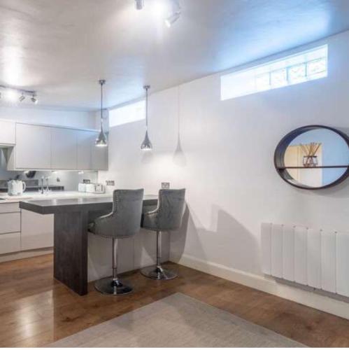 a kitchen with a bar with chairs and a mirror at The Gardners apartment in City centre with parking in Edinburgh