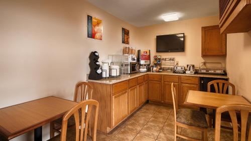 a kitchen with wooden cabinets and a table and chairs at Super 8 by Wyndham McGehee in McGehee