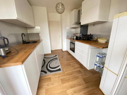 une cuisine avec des armoires blanches et un plancher en bois dans l'établissement Apartment 2 Chambres avec 2 Balcons, Évry-Courcouronnes