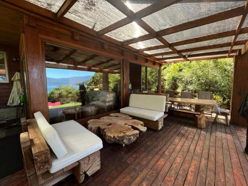 a screened porch with white furniture and a large window at Casa a orilla de Lago Panguipulli in Panguipulli