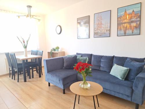 Una sala de estar con un sofá azul y una mesa. en Grand Apartament - prywatny parking, blisko Szpital Arkońska, en Szczecin