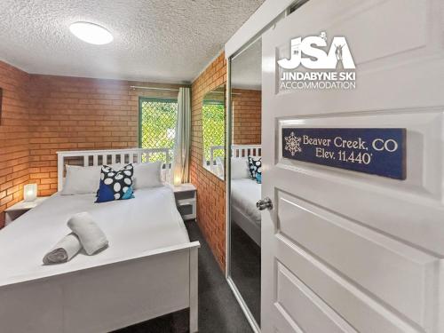 a room with two beds and a door with a sign at Sunrise 5 in Jindabyne