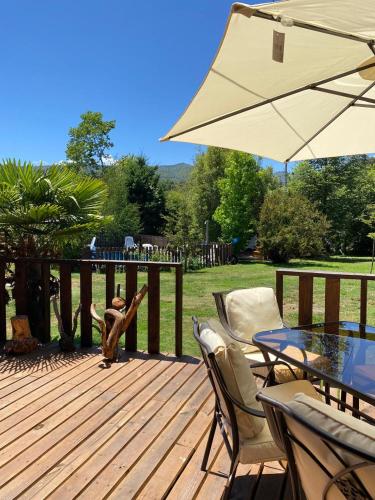 una terraza de madera con mesa, sillas y sombrilla en Cabañas don Francisco, en Recinto