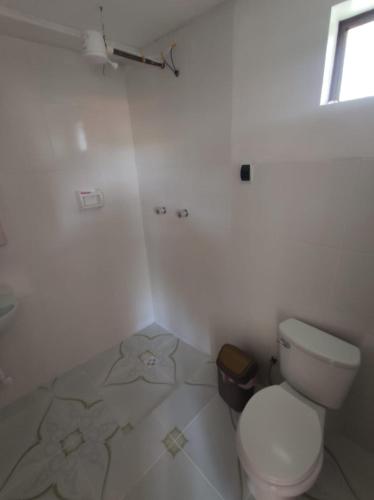 a white bathroom with a toilet and a window at Hostal Margarita in Comunidad Challapampa