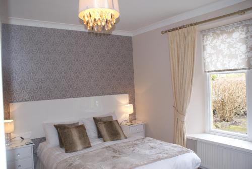 a bedroom with a bed with a chandelier and a window at The Coppice - including off-site health club in Windermere