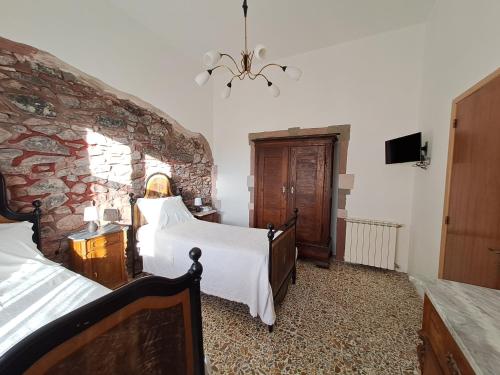 a bedroom with two beds and a stone wall at La Casa di Zietta in Santu Lussurgiu