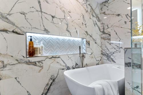 a bathroom with a white tub and a marble wall at Upscale Resort House, Views, Saltwater Pool, Spa in Spring Valley