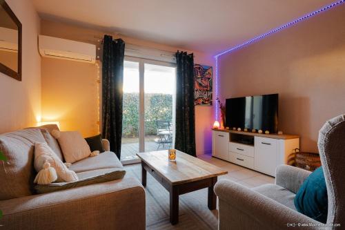 un salon avec un canapé et une télévision dans l'établissement Epicur Forest - Love room romantique avec jacuzzi privé, à Brax