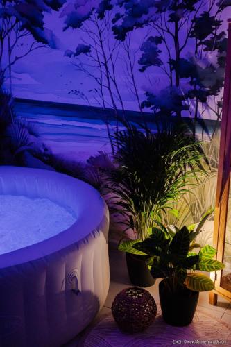 une baignoire installée dans une pièce ornée de plantes dans l'établissement Epicur Forest - Love room romantique avec jacuzzi privé, à Brax