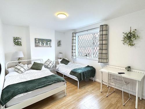 a bedroom with two beds and a desk and a window at 3 Twin Bedroom Entire House Sleeps 10 Driveway Parking near Coventry University and City Center in Coventry