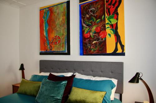 a bedroom with three paintings on the wall and a bed at Wooster Square Gems in New Haven