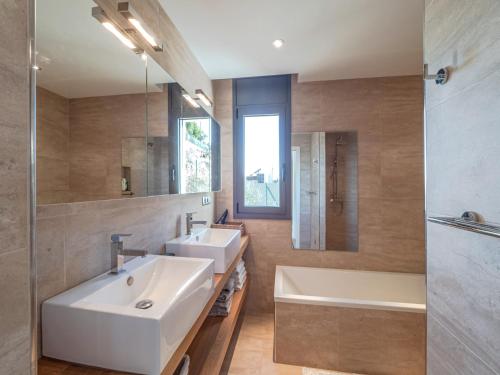 Un baño con dos lavabos, una bañera y un espejo. en House in Roses near Canyelles Beach, en Montjoi