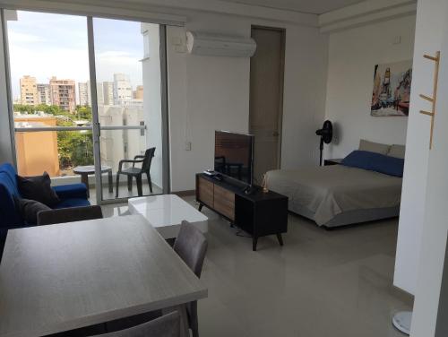 a bedroom with a bed and a living room with a view at Apartaestudio Jacuzzi Centro Comercial Gimnasio ALTOPRADO in Barranquilla