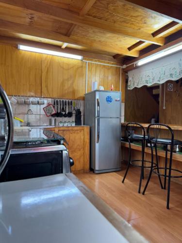 una cocina con nevera y algunas sillas. en Casa con vista a Futaleufú, en Futaleufú