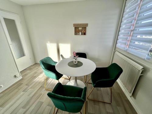 une salle à manger avec une table blanche et des chaises vertes dans l'établissement Cocon Cosy et Verdoyant - Private Parking, Breakfast, Wifi, Netflix, à Caen