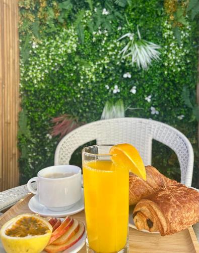une table avec un verre de jus d'orange et une assiette de pain dans l'établissement Cocon Cosy et Verdoyant - Private Parking, Breakfast, Wifi, Netflix, à Caen