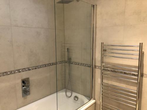 a shower with a glass door in a bathroom at Luxury Hampstead Mews House, Close to City Centre in London
