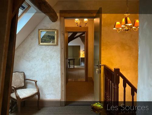 un couloir avec une chaise et une porte ouverte dans l'établissement Les sources, à Sainte-Marguerite-de-Carrouges