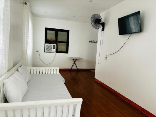 Sofias Private Farm House في Alfonso: غرفة نوم بها سرير أبيض وجهاز تلفزيون معلق على الحائط