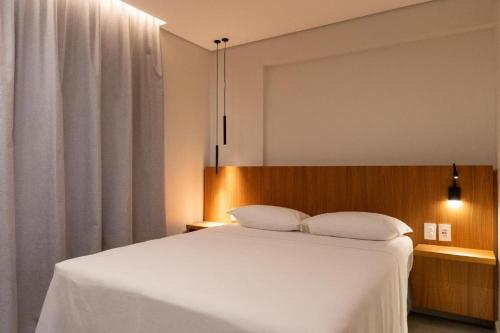 a bedroom with a white bed with a wooden headboard at Apto Salinas Premium - 2 quartos - 1 suíte in Salinópolis