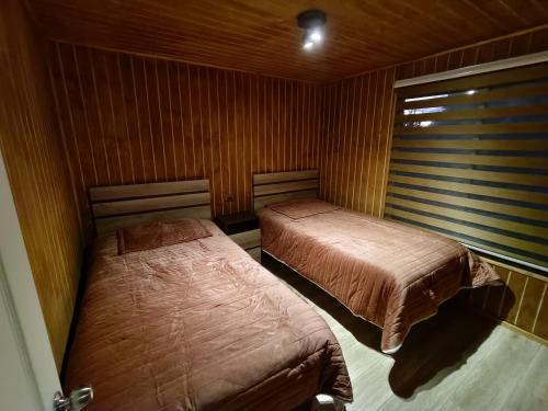two beds in a room with wood paneling at Cabaña Drak Bosque y Mar 2 in Tomé
