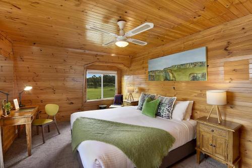 Un dormitorio con una cama y una pared de madera. en Hunter Valley Lodge & Retreat - Stunning Country Lodge, en Nulkaba