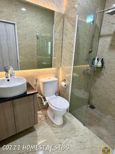 a bathroom with a toilet and a shower and a sink at Cozzi Homestay Sibu in Sibu