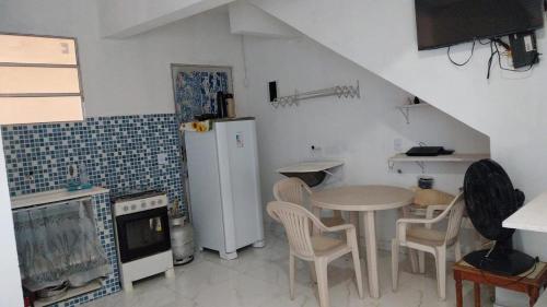 a small kitchen with a table and a refrigerator at Residencial Praia Quente casas in Nova Viçosa