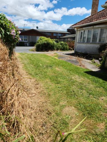 a house with a grassy yard in front of a house at Cedar Lodge Motel Hamilton in Hamilton