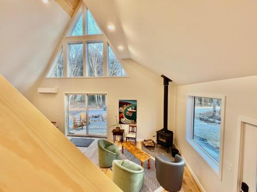 a living room with a vaulted ceiling with windows at Chickadee A-Frame in Freeport