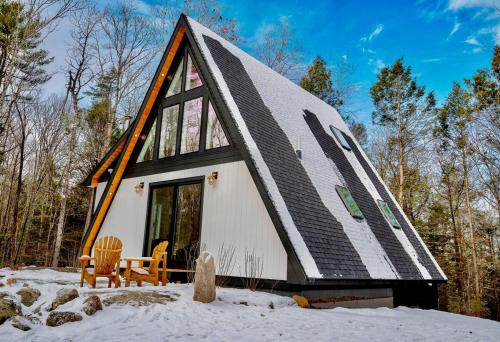 a small house with a gambrel roof in the snow at Chickadee A-Frame in Freeport