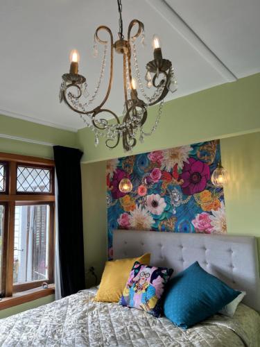a bedroom with a bed with a chandelier at Fantail Cottage in Opua