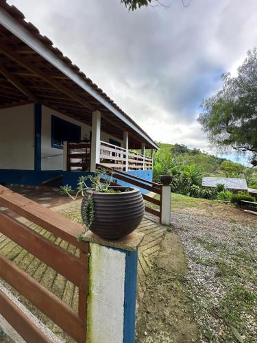 a house with a fence and a pot on a wall at Sítio São Pedro in São Bento do Sapucaí