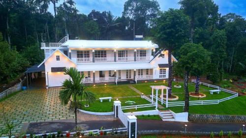 an aerial view of a large white house at Uthuppan's 2 bedroom first floor in Ūdumbanshola