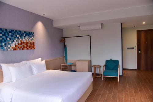 a bedroom with a white bed and a blue chair at The Vista Beach Resort Phan Thiết in Phan Thiet