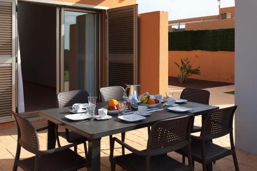 a black table with chairs and fruit on a patio at Villa con Piscina ,Vista Mar y campo de golf in Caleta De Fuste